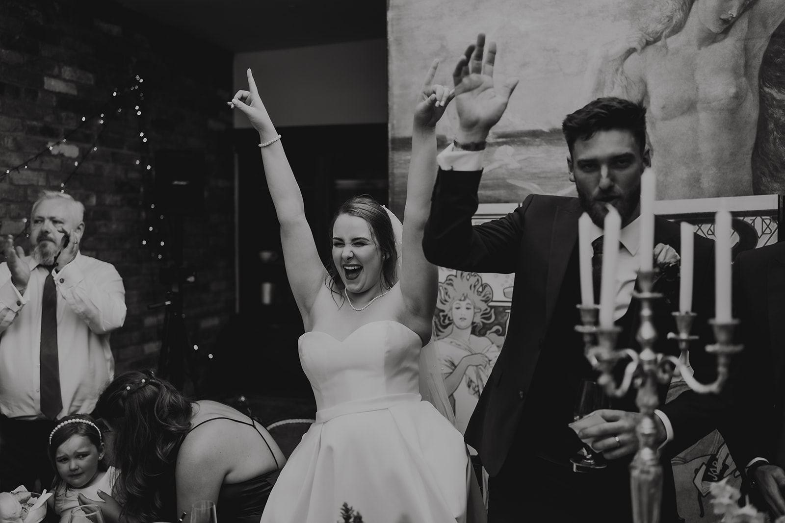 Candid black and white documentary photograph capturing a bride's joyful reaction during her wedding reception in Southend-on-Sea — unscripted emotional wedding photography by Lily & White Essex wedding photographer