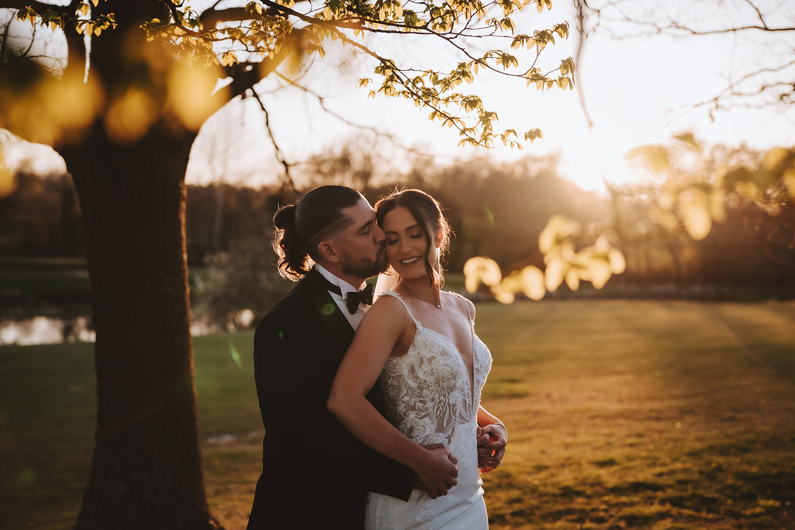 Groom kissing his bride on the cheek during golden hour couple portraits at Crondon park, Essex — editorial wedding photography by Lily & White