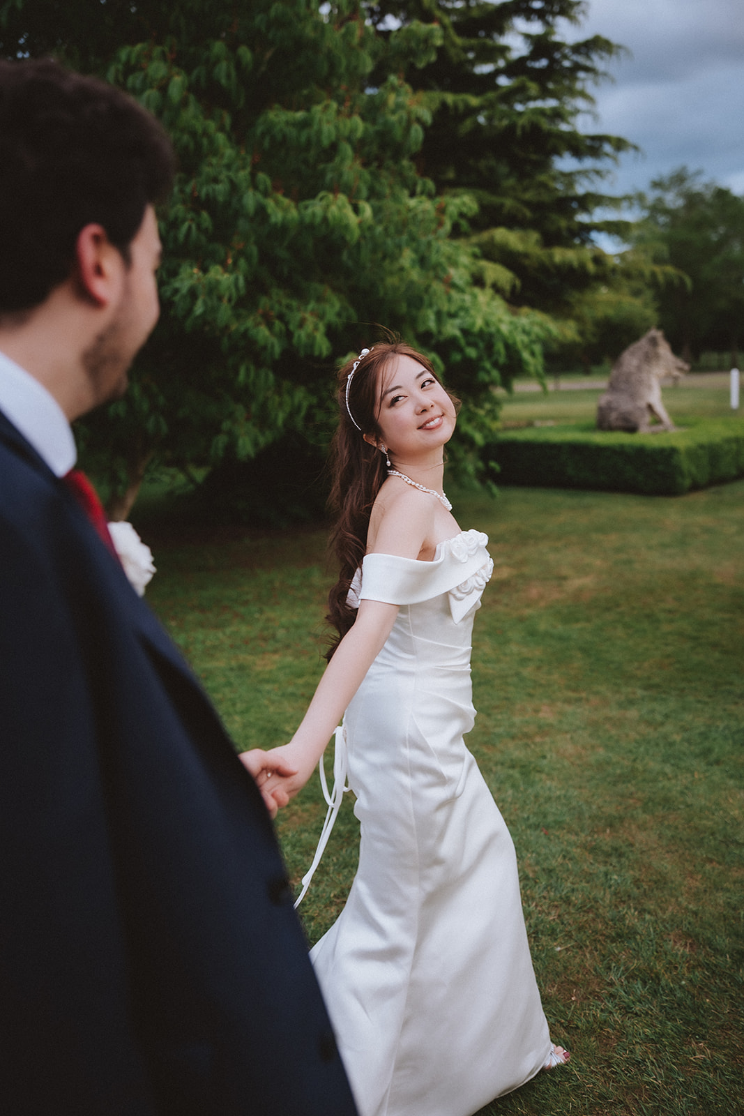 Cinematic wedding photography Essex; a bride leading her groom through landscaped gardens at a Chippenham Park country estate