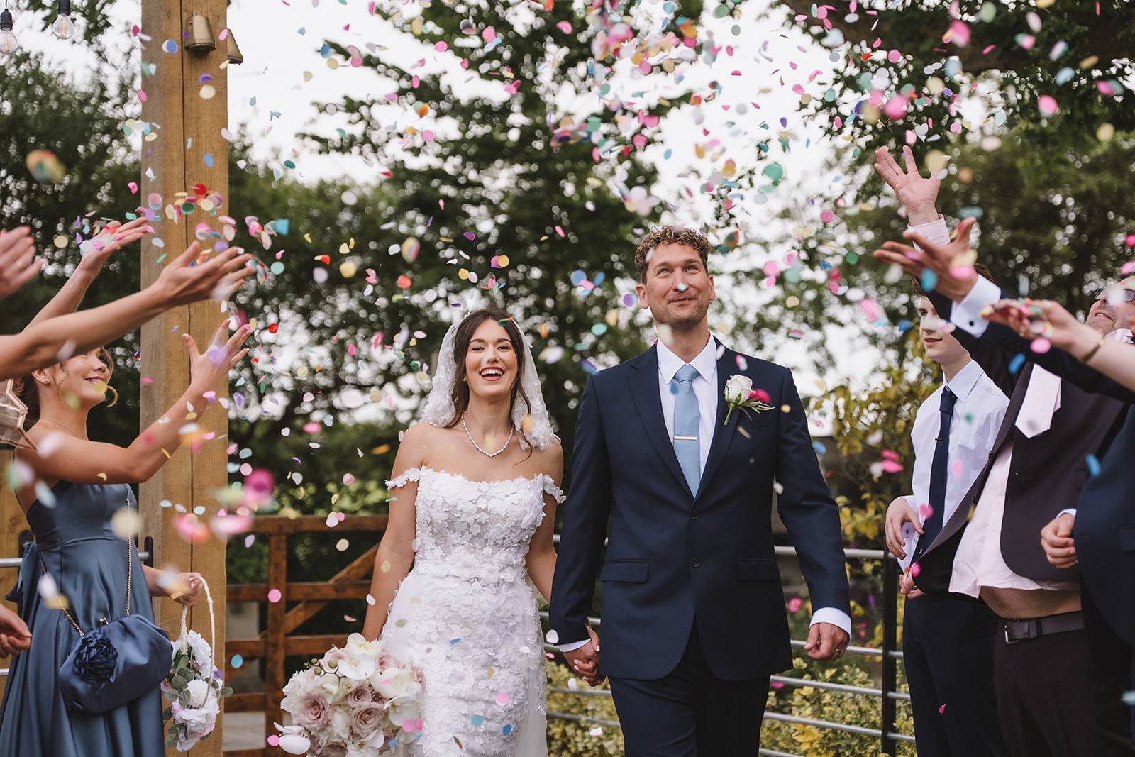 Vibrant and natural wedding photography in Essex, capturing a joyful confetti exit at Friern Manor wedding venue with a bride and groom laughing together during their ceremony celebration.