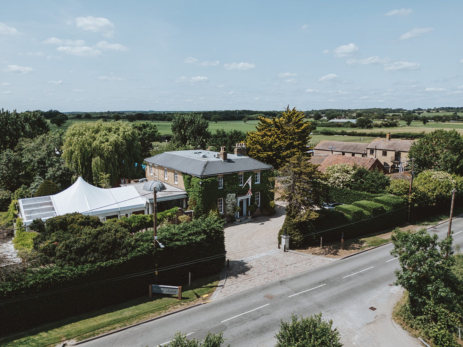 Aerial view of Friern Manor wedding venue in Dunton, Brentwood, showing the Georgian manor house, white marquee, and surrounding Essex countryside — drone photography by Lily & White