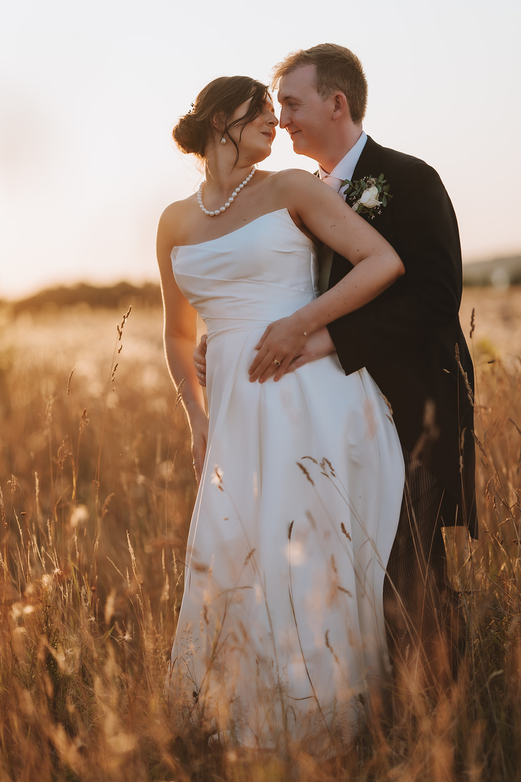 Cinematic wedding photography in Essex; a romantic couple portrait captured in a tall grass meadow during golden hour.