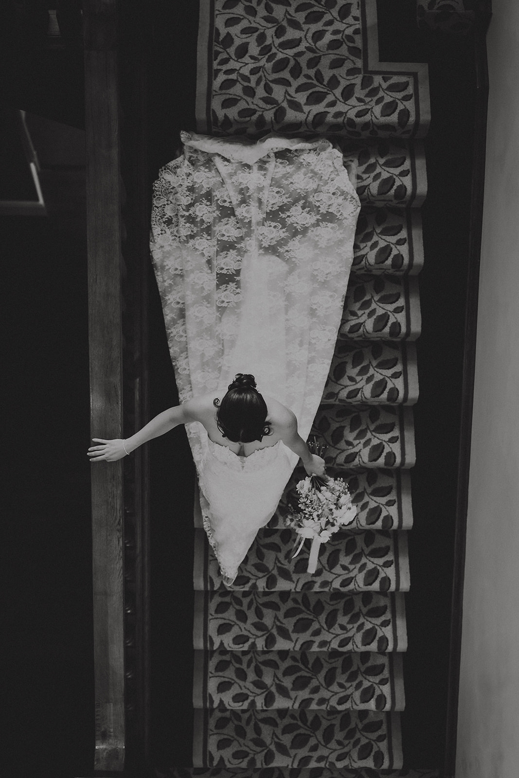 Overhead view of bride descending the grand staircase at Wivenhoe House in Colchester — creative architectural wedding photography by Lily & White
