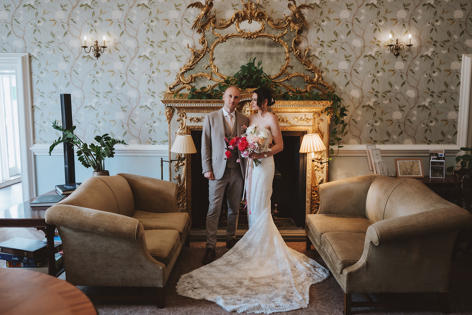 Bride and groom portrait in the elegant drawing room at Wivenhoe House with ornate gold mirror and period interiors — editorial wedding photography by Lily & White