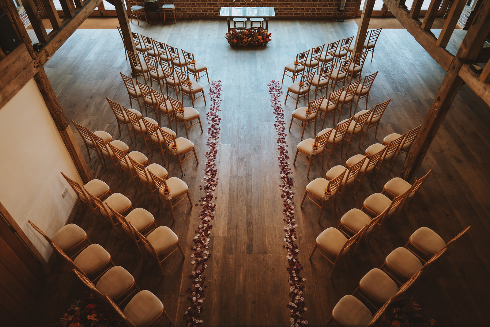 the Hay Barn at Blake Hall set for a ceremony, rose petals lining the aisle viewed from above.