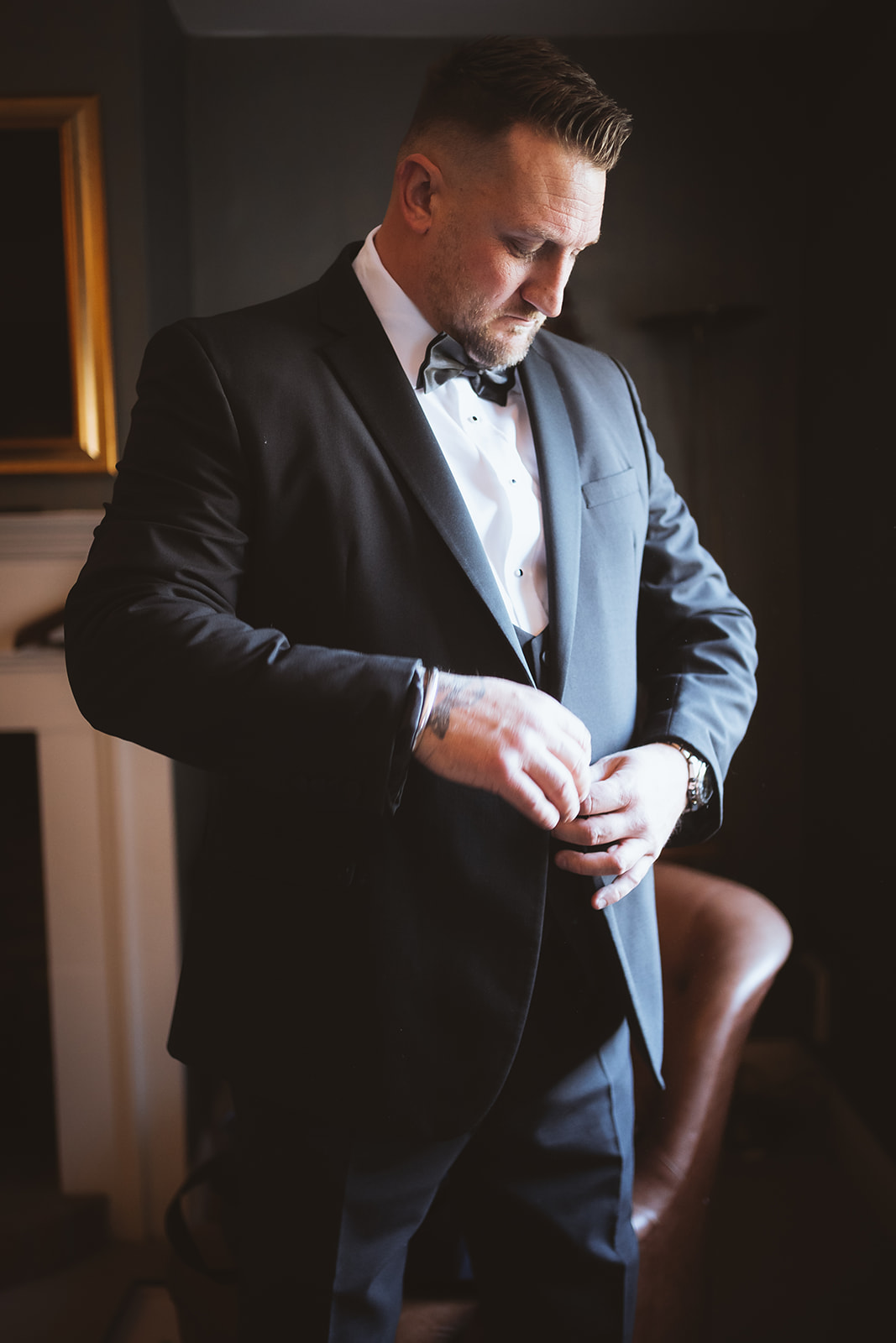 Candid documentary portrait of a groom fastening his cufflinks during wedding morning preparations at Mulberry House in Essex — editorial wedding photography by Lily & White