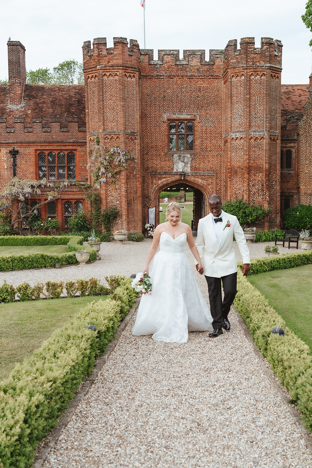 Jennifer and Toib walking hand in hand through the gardens at Leez Priory, Essex on their wedding day, photographed by Tel, Lily & White Photography
