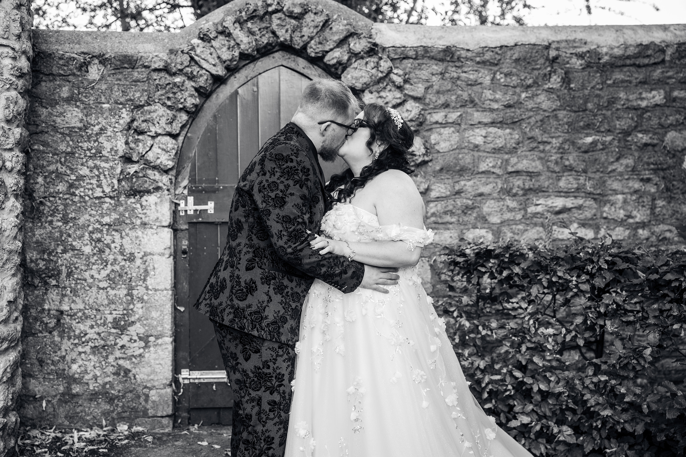 Bride and groom kissing by an arched door at Sudbury House, Faringdon