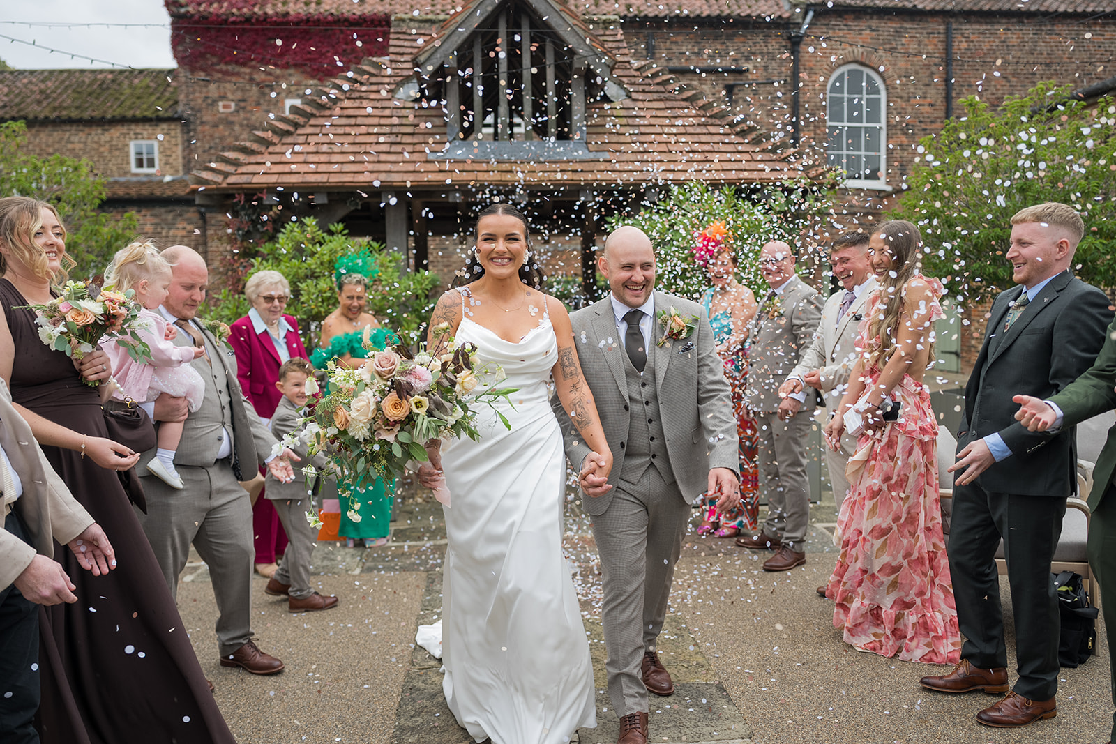 Sally and Callum walking through confetti at Hornington Manor